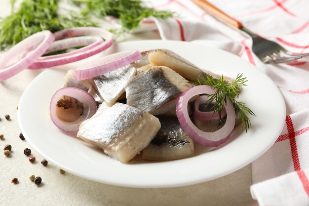 Concetto di pranzo con piatto di aringhe fresche su sfondo bianco con texture