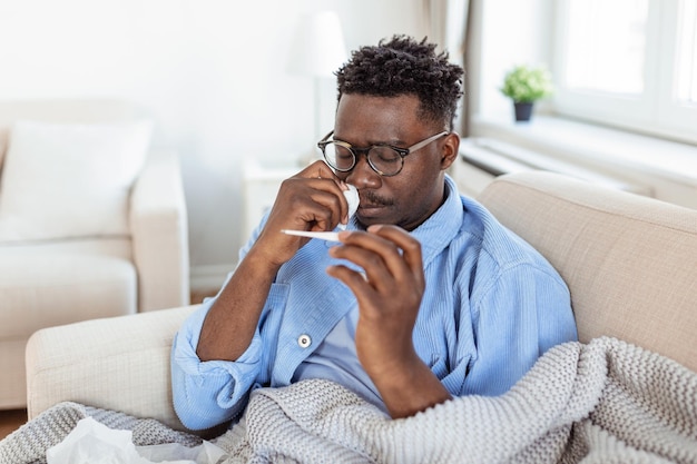 Concetto di problema di virus stagionale di malattia Uomo malato con influenza sdraiato sul letto guardando la temperatura sul termometro Uomo malato sdraiato a letto con febbre alta Influenza fredda coronavirus covid19