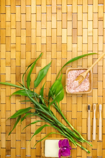 Concetto di prodotti ecologici con sale da bagno, foglie di bambù e spazzolino da denti sul tappetino in legno