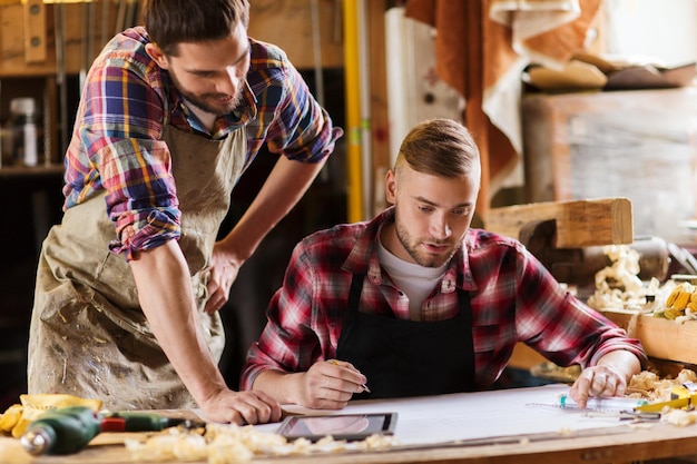 concetto di professione, falegnameria, falegnameria e persone - due falegnami con righello e progetto in officina