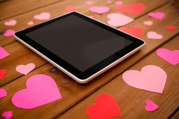 concetto di pubblicità, romanticismo, giorno di San Valentino e vacanze - primo piano del computer tablet pc e cuori su legno