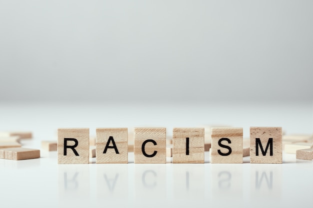 Concetto di razzismo e incomprensione tra persone, pregiudizio e discriminazione. Blocco di legno con parola razzismo