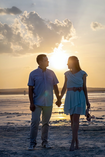 Concetto di relazione felice Fotografia verticale Coppia innamorata uomo e donna al tramonto si tengono per mano