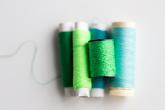 concetto di ricamo, artigianato, cucito e sartoria: bobine di filo verde e blu sul tavolo