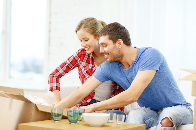 concetto di riparazione, costruzione e casa - coppia sorridente che disimballa gli indumenti da cucina