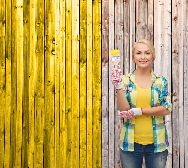 concetto di riparazione, costruzione e manutenzione - donna sorridente con il pennello