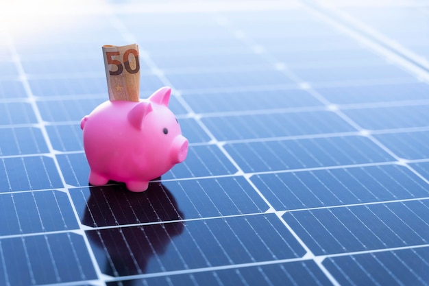 Concetto di risparmio energetico con pannelli solari e un salvadanaio con cinquanta euro