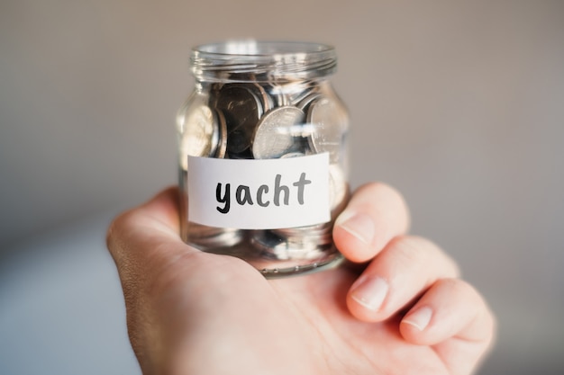 Concetto di risparmio per yacht - Vaso di vetro con monete e iscrizione.