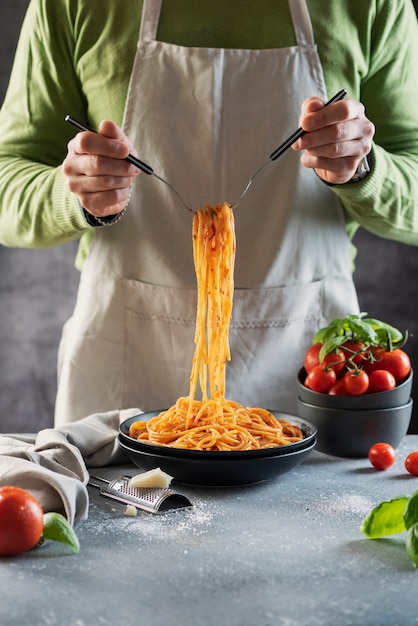 Concetto di ristorante. Uomo che cucina gli spaghetti italiani con pomodoro e basilico,