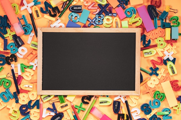 Concetto di ritorno a scuola. Attrezzatura di istruzione e della lavagna su fondo arancio.