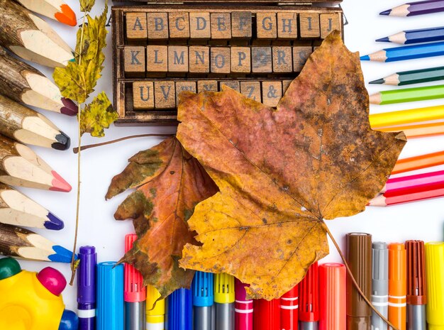 Concetto di ritorno a scuola Lettere in legno Alfabeto inglese in scatola moderna e accessori per lo studio su superficie bianca Ciao concetto di scuola