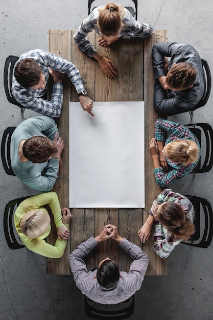 Concetto di riunione di pianificazione del lavoro di squadra di affari di hipster, persone sedute intorno al tavolo con carta bianca