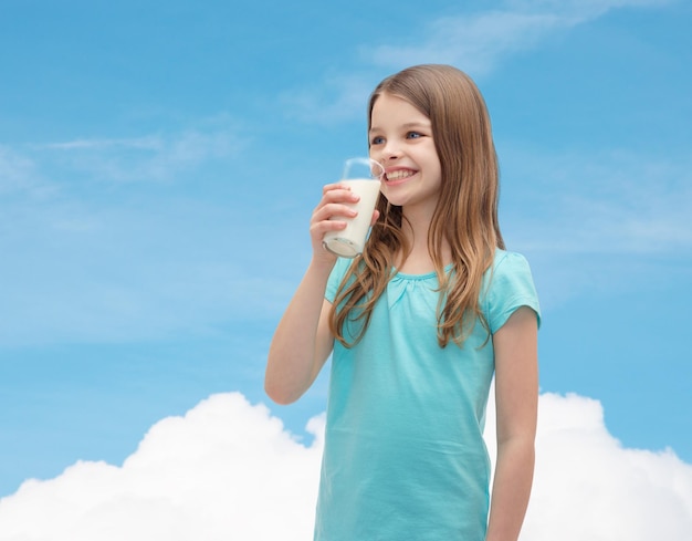 concetto di salute e bellezza - bambina sorridente che beve latte in vetro