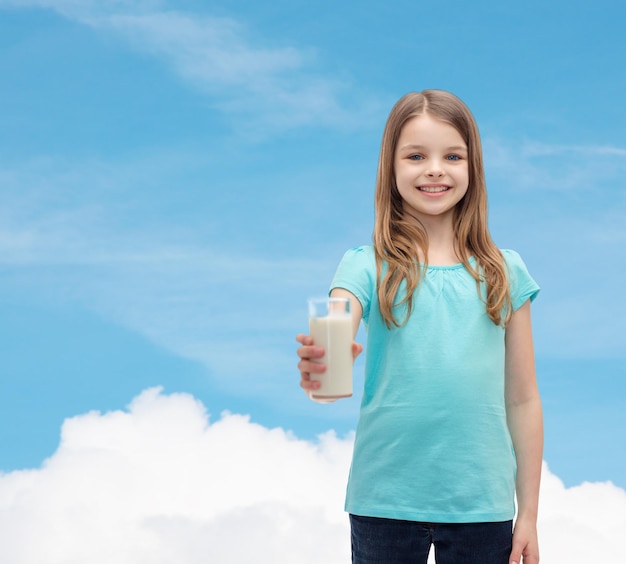 concetto di salute e bellezza - bambina sorridente che dà un bicchiere di latte