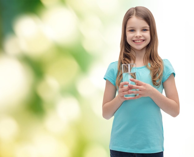 concetto di salute e bellezza - bambina sorridente con un bicchiere d'acqua