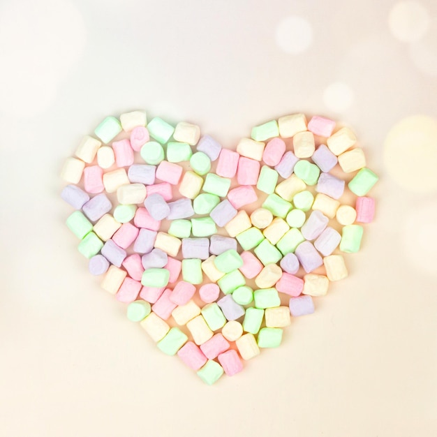 Concetto di San Valentino. Bellezza marshmallow a forma di cuore su sfondo pastello con bokeh rotondo incandescente, primo piano. Concetto minimale creativo e lunatico.