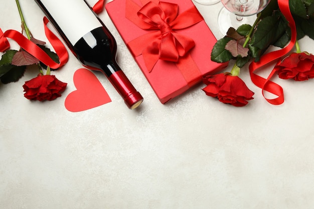 Concetto di San Valentino con rose, vino e confezione regalo su sfondo bianco con texture
