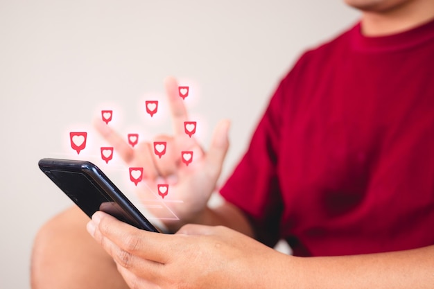 Concetto di San Valentino L'uomo usa il segno della mano per dare amore attraverso uno smartphone Effetto visivo a forma di cuore