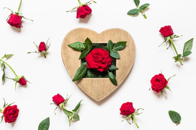 Concetto di San Valentino rose rosse e cuore di legno su sfondo bianco