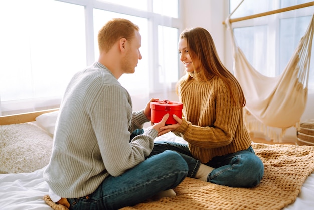 Concetto di San Valentino Scambio di doni Giovane coppia a casa che celebra il giorno di San Valentino