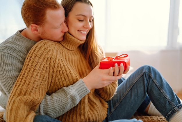 Concetto di San Valentino Scambio di doni Giovane coppia a casa che celebra il giorno di San Valentino