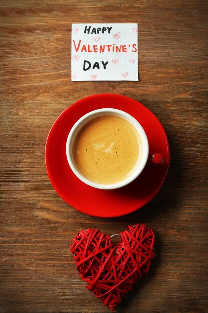 Concetto di San Valentino Tazza di caffè con cuore rosso e nota su sfondo tavolo in legno