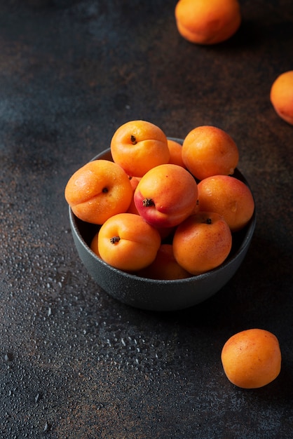 Concetto di sano cibo vegano con albicocche dolci in uno sfondo scuro,