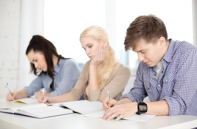 concetto di scuola e istruzione - gruppo di studenti stanchi con quaderni a scuola