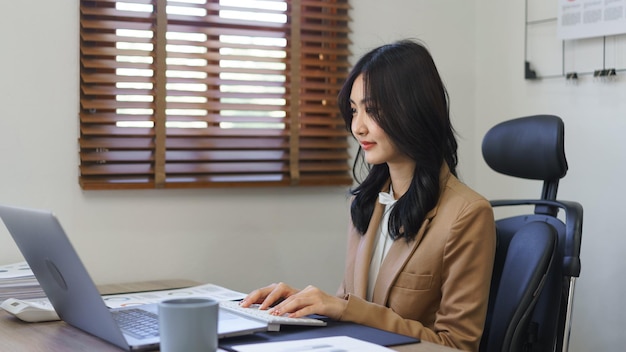 Concetto di segretario La segretaria femminile sta lavorando e digitando il rapporto di lavoro sul computer portatile in ufficio