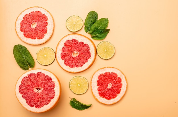 Concetto di sfondo estivo pompelmo a fette, lime, menta su sfondo arancione