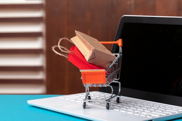 Concetto di shopping online. Carrello, laptop sulla scrivania