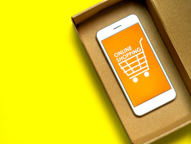 Concetto di shopping online. Parole "Shopping online" e icona del carrello su sfondo arancione sullo schermo dello smartphone.