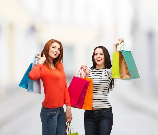 concetto di shopping, vendita e regali - due adolescenti sorridenti con borse della spesa in strada