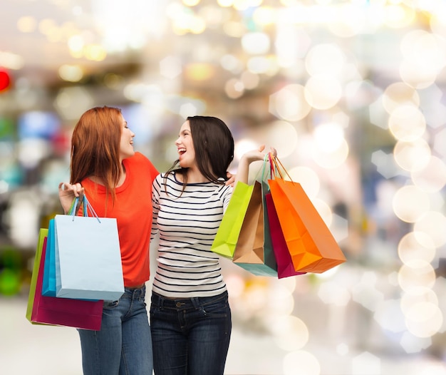 concetto di shopping, vendita e regali - due adolescenti sorridenti con borse della spesa