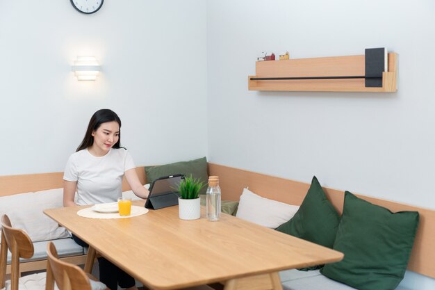 Concetto di soggiorno una donna che utilizza il suo dispositivo elettronico per lavorare in remoto nell'accogliente sala della caffetteria.