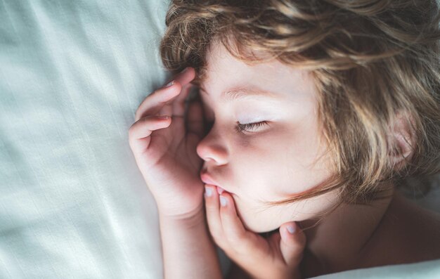 Concetto di sonno dei bambini Bambino che dorme da solo in un comodo letto con lenzuola bianche