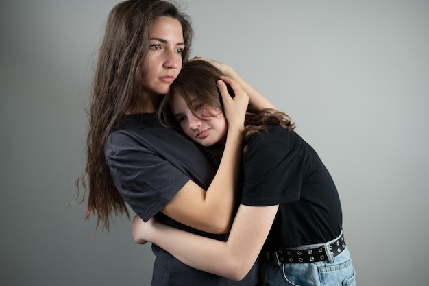 Concetto di sostegno e fiducia della famiglia La mamma abbraccia e conforta la figlia adolescente su sfondo grigio Foto di alta qualità