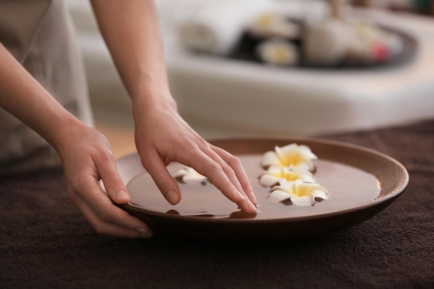 Concetto di spa Mani femminili con ciotola e fiori esotici