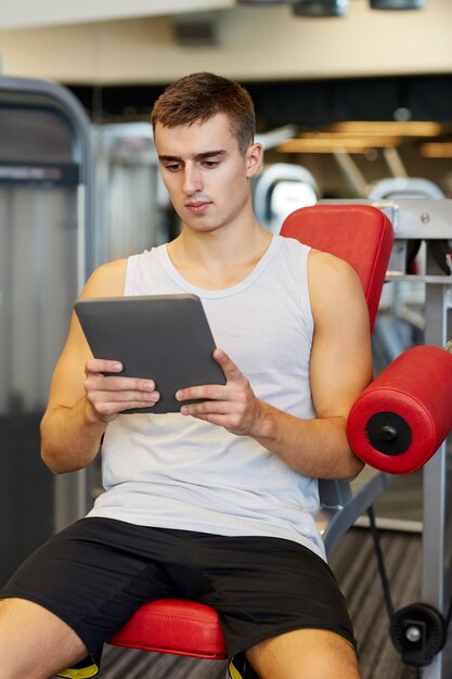 concetto di sport, bodybuilding, stile di vita, tecnologia e persone - giovane con computer tablet pc in palestra