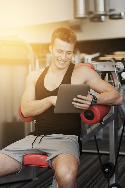 concetto di sport, bodybuilding, stile di vita, tecnologia e persone - giovane sorridente con computer tablet pc in palestra