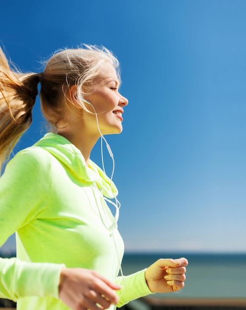 concetto di sport e stile di vita - donna che fa correre con gli auricolari all'aperto