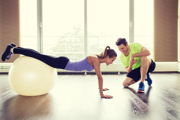 concetto di sport, fitness, stile di vita e persone - uomo e donna sorridenti che si allenano con la palla ginnica in palestra