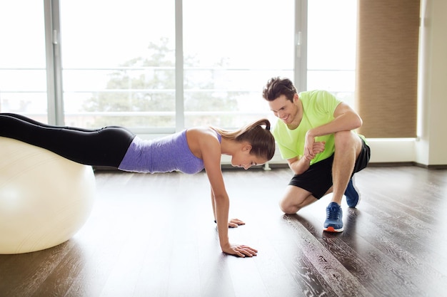 concetto di sport, fitness, stile di vita e persone - uomo e donna sorridenti che si allenano con la palla ginnica in palestra