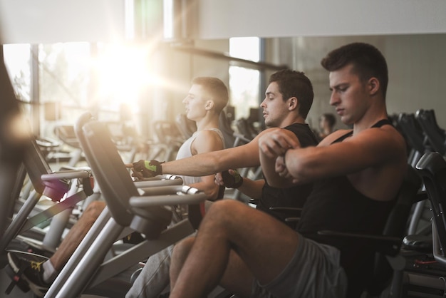 concetto di sport, fitness, stile di vita, tecnologia e persone - uomini che si allenano sulla cyclette in palestra