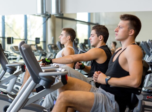 concetto di sport, fitness, stile di vita, tecnologia e persone - uomini che si allenano sulla cyclette in palestra