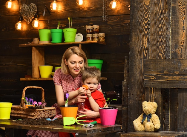 Concetto di spruzzatura Donna e bambino che spruzzano giovane pianta in vaso Madre e bambino che spruzzano con bottiglia spray Acqua di spruzzatura