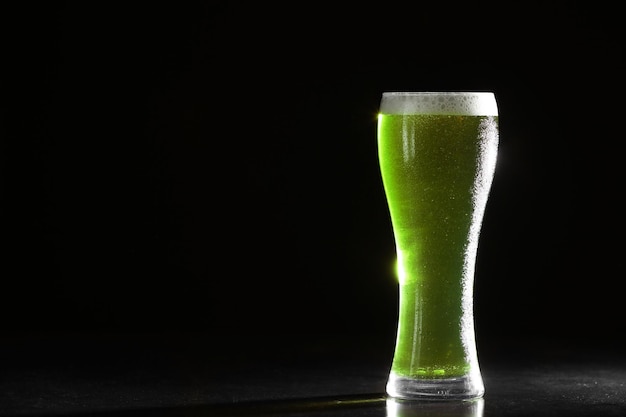 Concetto di St Patrick Day Bicchiere di birra verde su sfondo nero