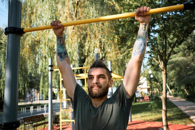 Concetto di stile di vita attivo Giovane uomo caucasico bello si tira su sul campo sportivo di strada