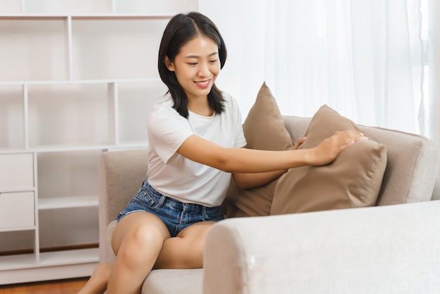 Concetto di stile di vita domestico Giovane donna seduta sul divano per disporre i cuscini per il relax a casa