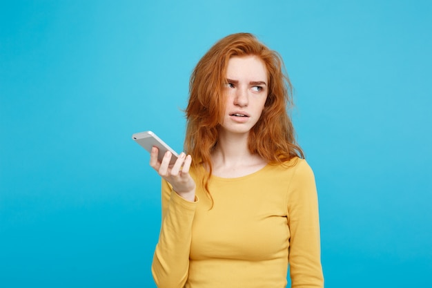 Concetto di stile di vita e tecnologia - Ritratto di allegra ragazza di capelli rossi zenzero felice con gioiosa ed eccitante sorridente alla telecamera. Isolato su sfondo blu pastello. Copia spazio.